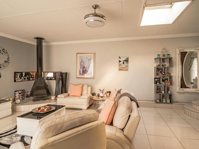 Spacious living room featuring a modern freestanding fireplace, tiled flooring, and a skylight that provides ample natural light.