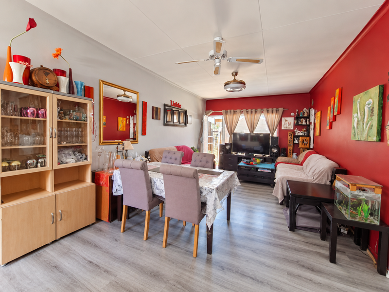 Open-plan living and dining area featuring laminate flooring, a ceiling fan, and direct access to the outdoor space through a sliding glass door.