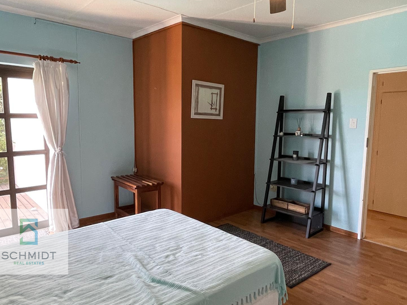 A bedroom featuring laminate flooring, built-in cupboards, and a glass panel door providing access to an outdoor area.