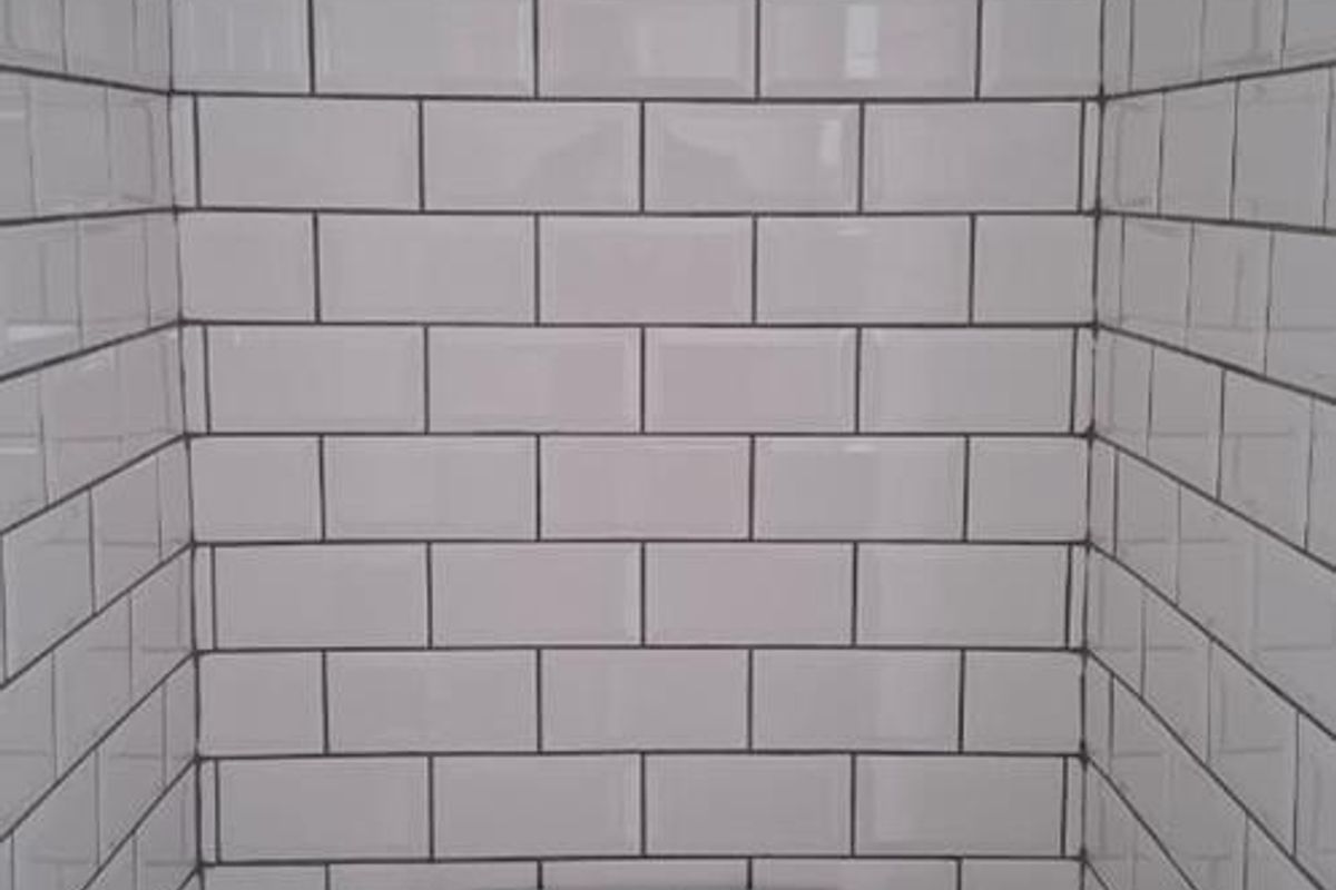 A compact, clean bathroom featuring modern white subway wall tiles and a standard toilet fixture.