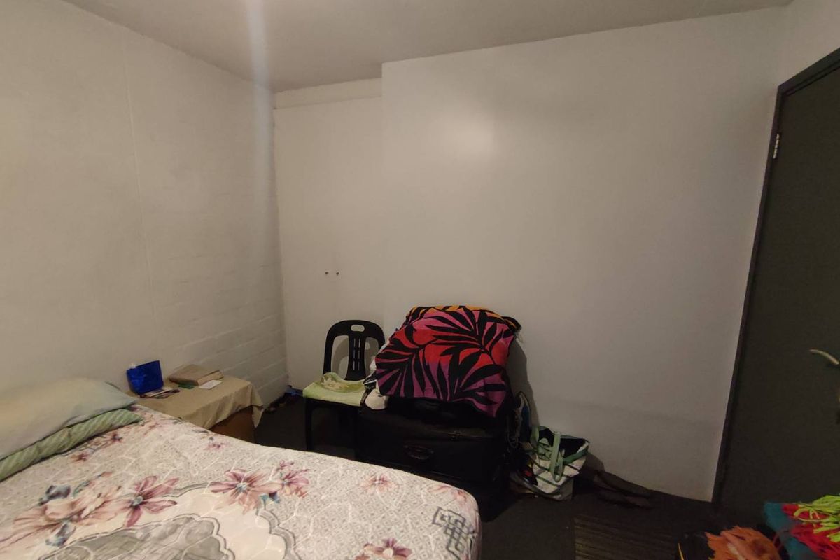 A simple bedroom featuring plain white walls and a standard interior door, providing a functional space for rest.