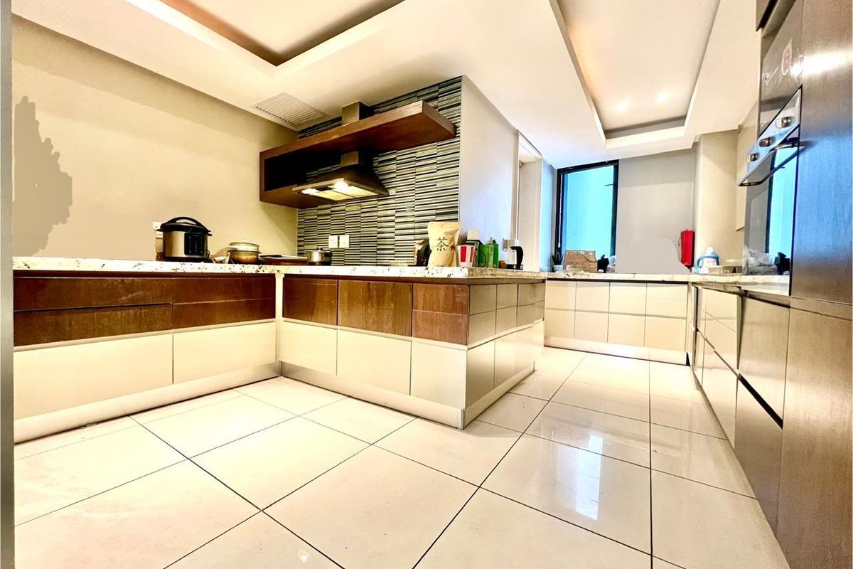 Modern kitchen featuring two-tone cabinetry, stone countertops, integrated oven, extractor fan, and sleek tiled flooring with recessed ceiling lighting.