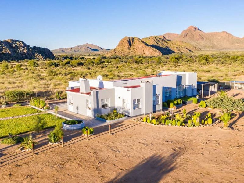 Aerial view of a well-maintained residential property set in a vast, arid landscape with mountain views.