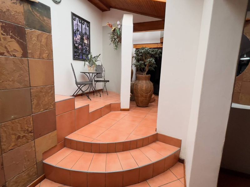 An inviting entry foyer featuring terracotta-style tiled steps, a textured stone feature wall, and a warm timber-lined ceiling.
