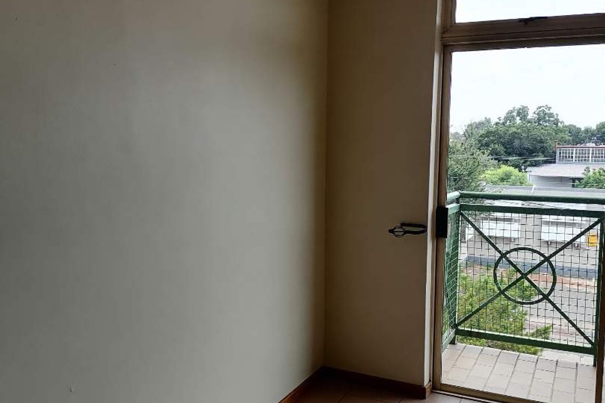 An empty bedroom featuring tiled flooring and a sliding glass door providing direct access to a private balcony.