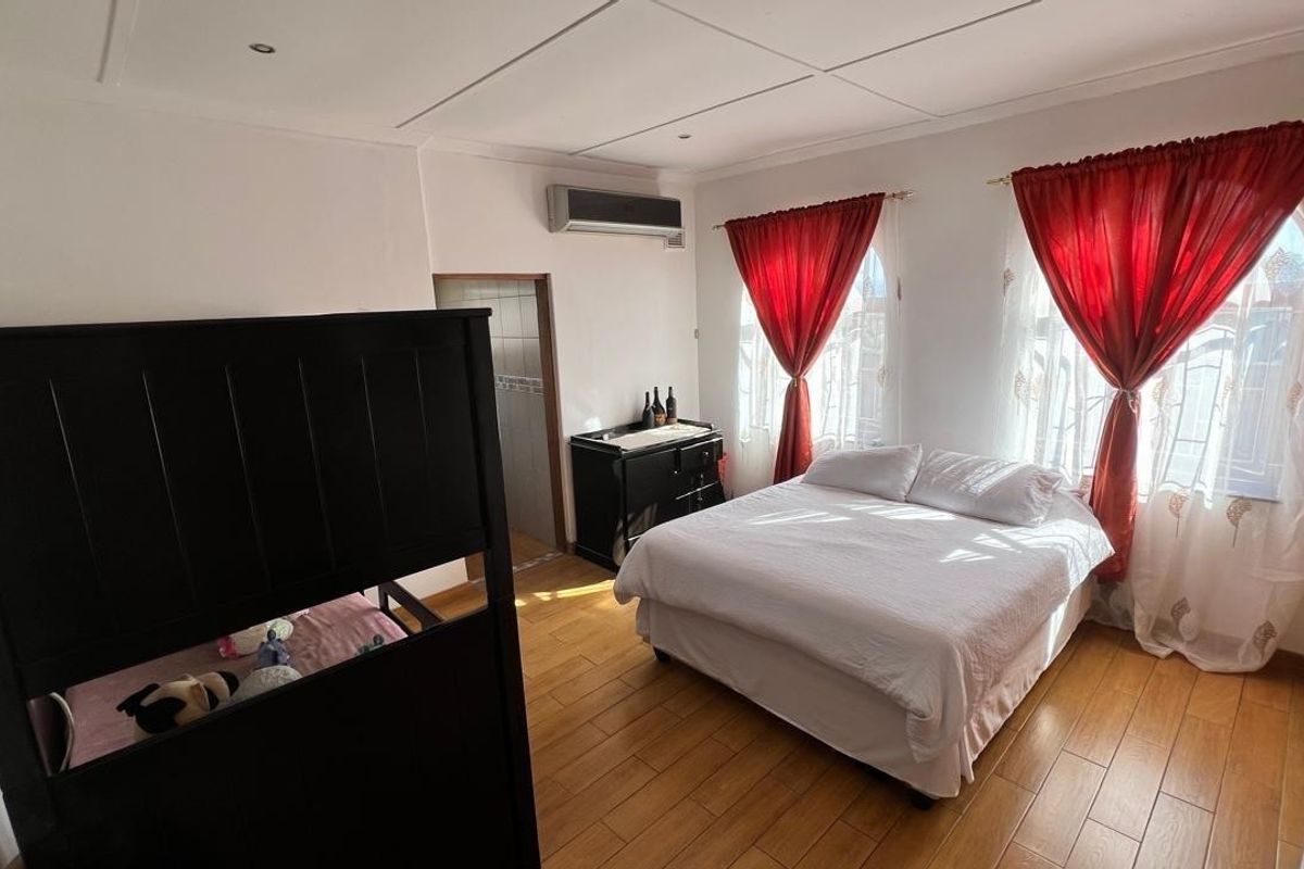 A bedroom featuring tiled flooring, an integrated air conditioning unit, and recessed ceiling lighting, providing a functional and comfortable living space.