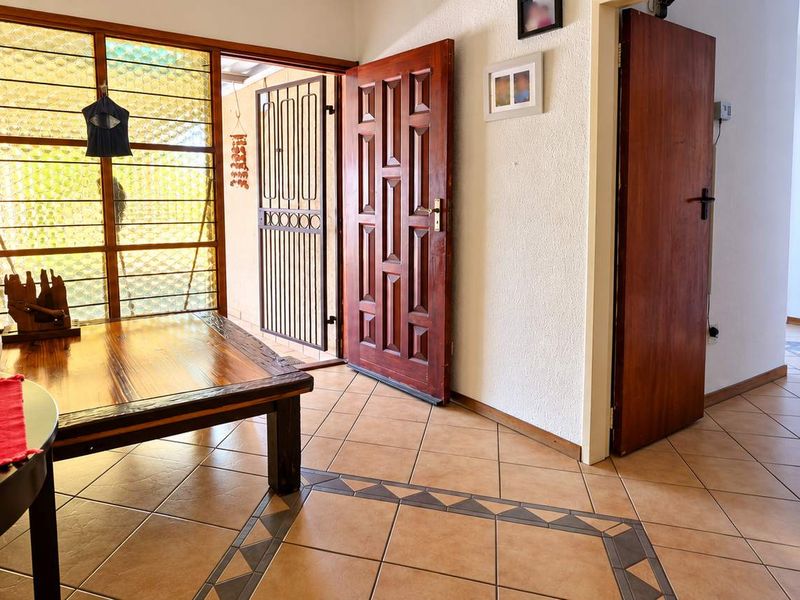 Entrance hall featuring tiled flooring, a solid timber front door, and a security gate, leading into the interior living spaces.