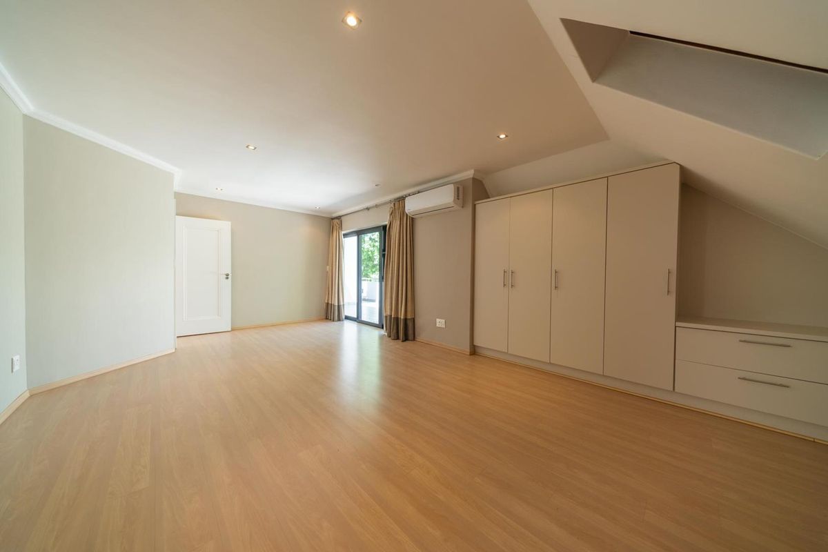 Spacious bedroom featuring laminate flooring, built-in cupboards, recessed lighting, and a split-system air conditioner with access to an outdoor area.