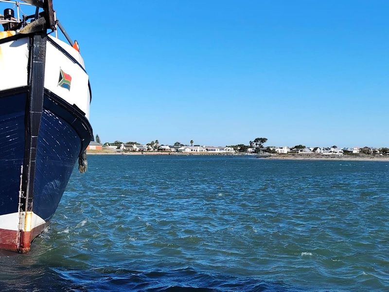 A scenic view across the water towards a coastal residential area, featuring a boat in the foreground.