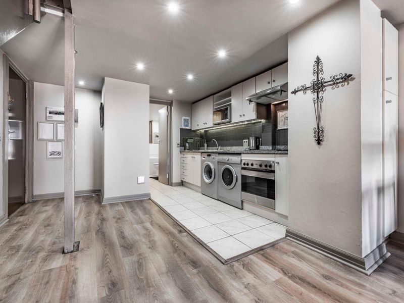 Modern kitchen featuring granite countertops, integrated appliances, stainless steel oven, extractor fan, and a combination of tiled and laminate flooring.