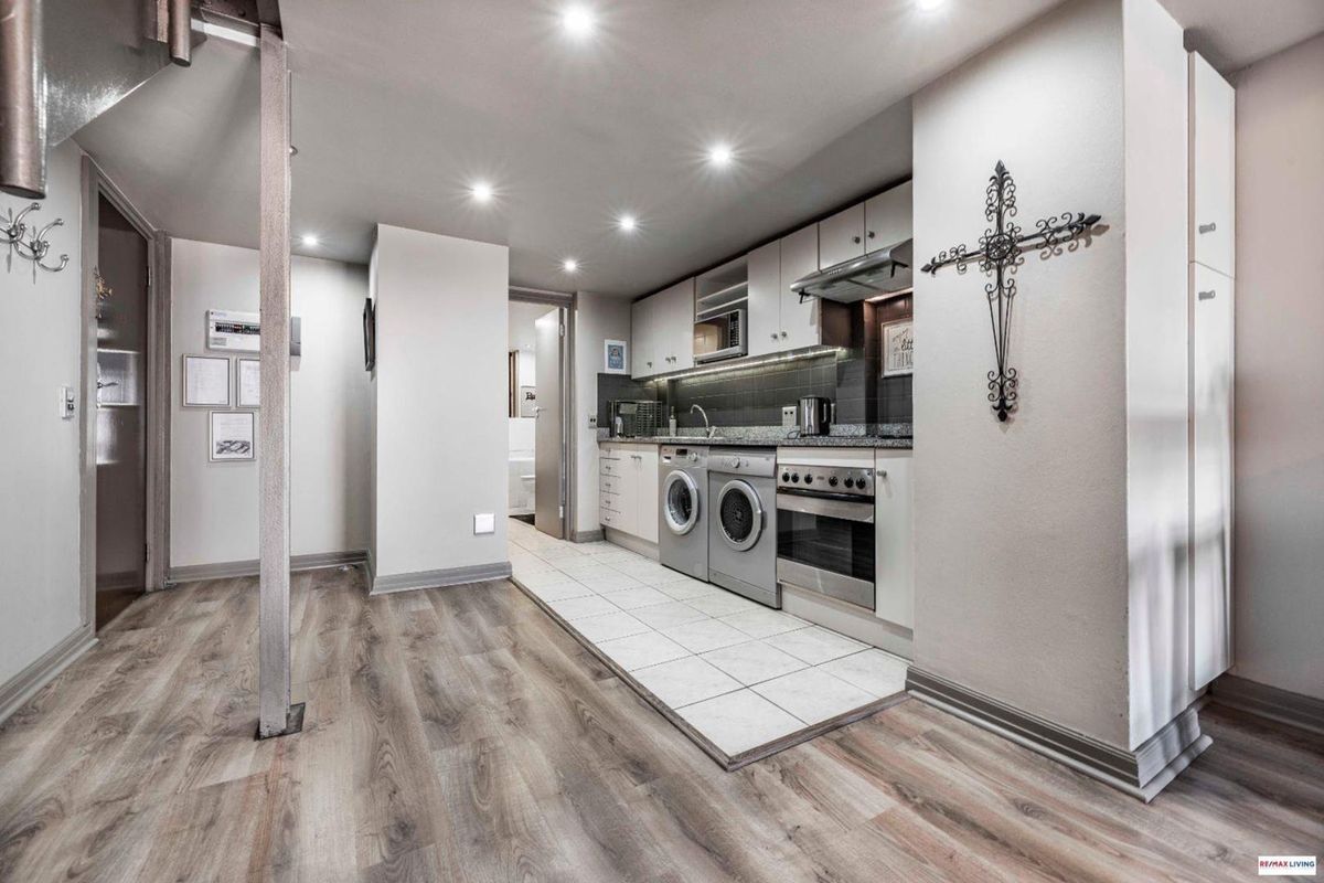 Modern kitchen featuring granite countertops, integrated appliances, stainless steel oven, extractor fan, and a combination of tiled and laminate flooring.
