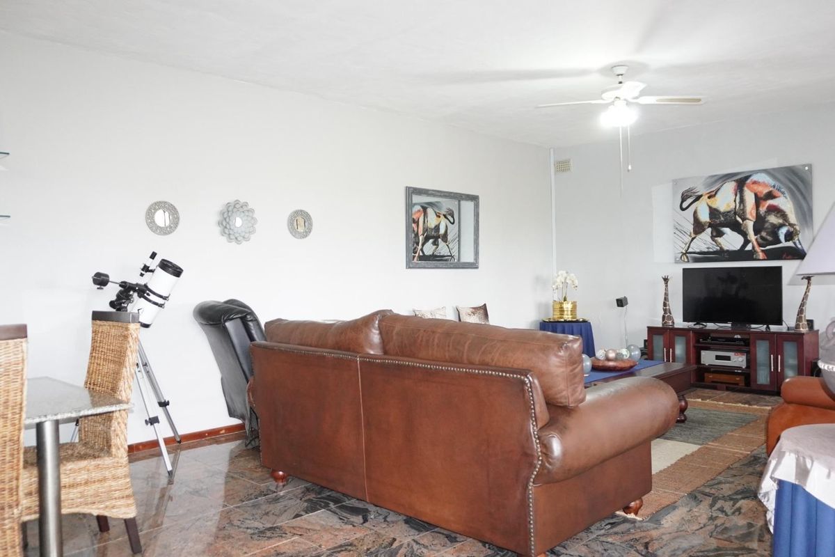 A spacious living room featuring tiled flooring and a ceiling fan, offering a comfortable area for relaxation and entertainment.