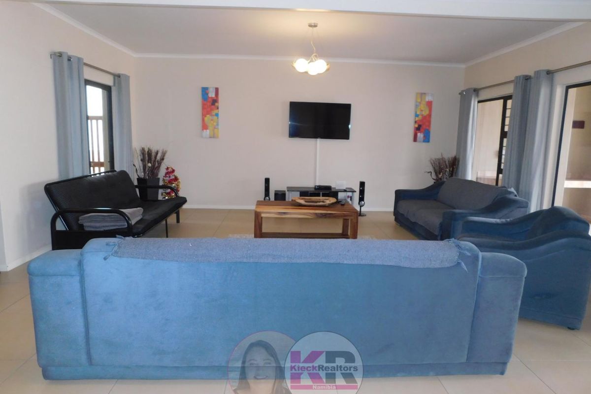 Spacious living room featuring neutral tiled flooring, cove cornicing, and large sliding glass doors providing access to the exterior.