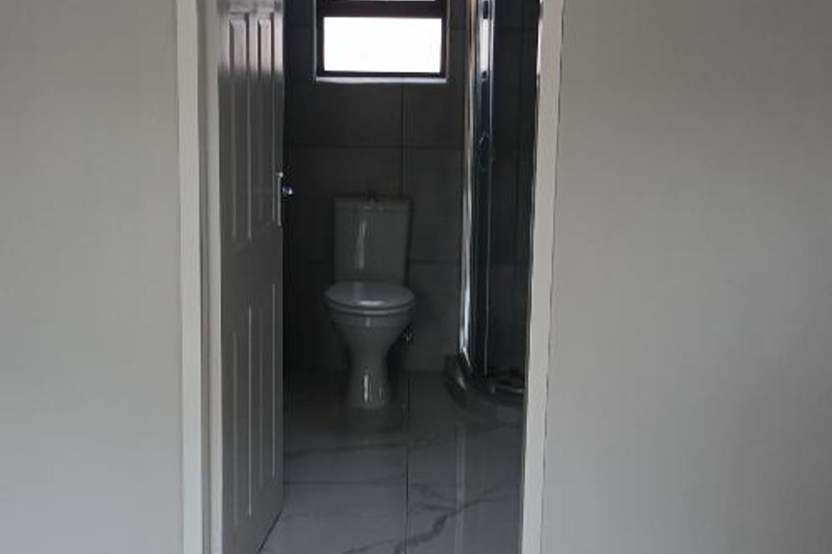 A view into a modern bathroom featuring marble-look porcelain floor tiles, a toilet, and a shower enclosure.