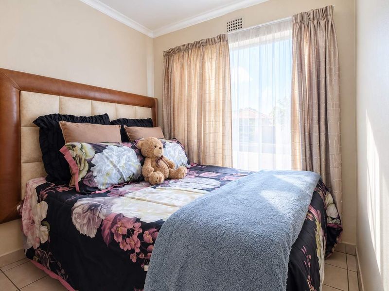 A compact bedroom featuring tiled flooring and a window with curtain tracks, providing natural light.