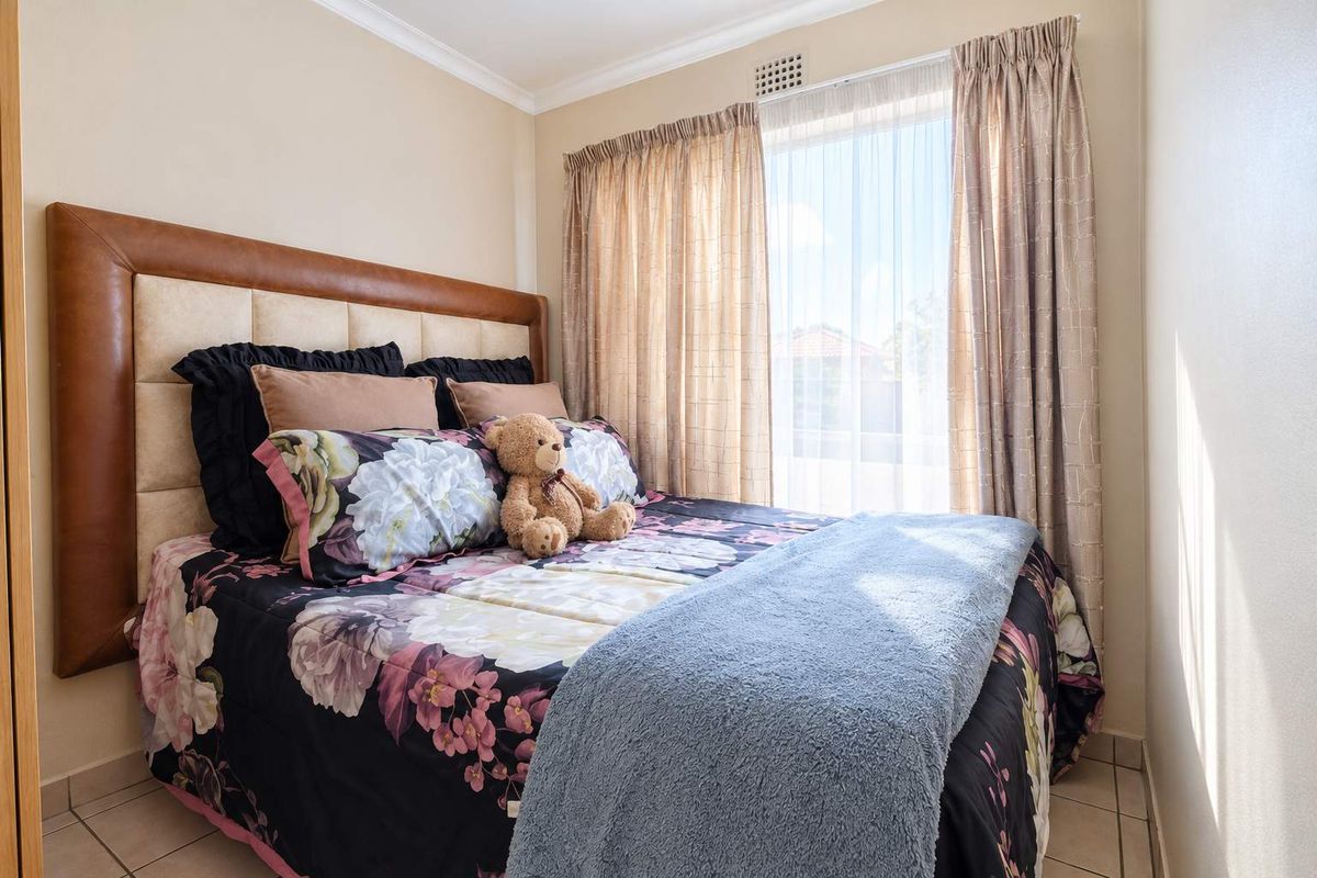 A compact bedroom featuring tiled flooring and a window with curtain tracks, providing natural light.