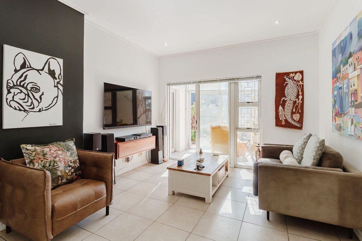 Bright living room featuring tiled flooring, a dark accent wall, and large sliding glass doors providing access to the patio area.