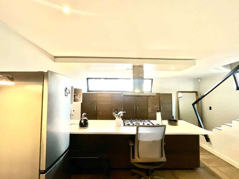 Modern kitchen featuring a central island with a built-in gas cooktop, stainless steel extractor fan, and dark wood cabinetry with ample storage space.