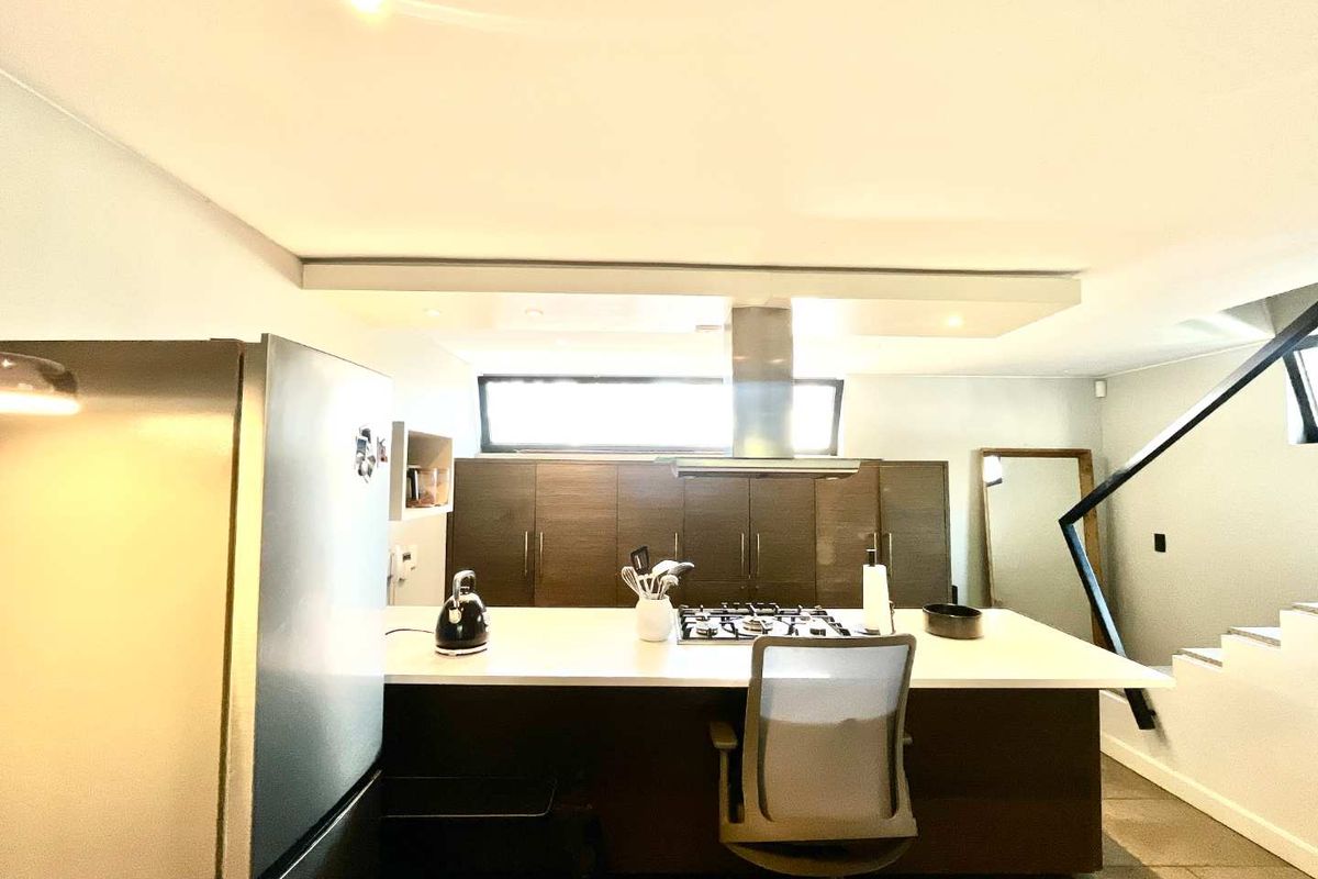 Modern kitchen featuring a central island with a built-in gas cooktop, stainless steel extractor fan, and dark wood cabinetry with ample storage space.