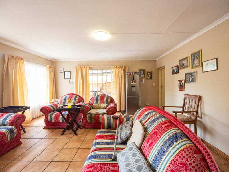 A spacious living room featuring tiled flooring, coved ceilings, and natural light through a sliding glass door.