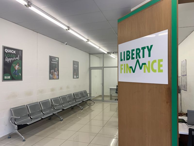 Commercial office entry area featuring tiled flooring, fluorescent lighting, and a glass partition, currently utilized as a waiting area for a finance office.