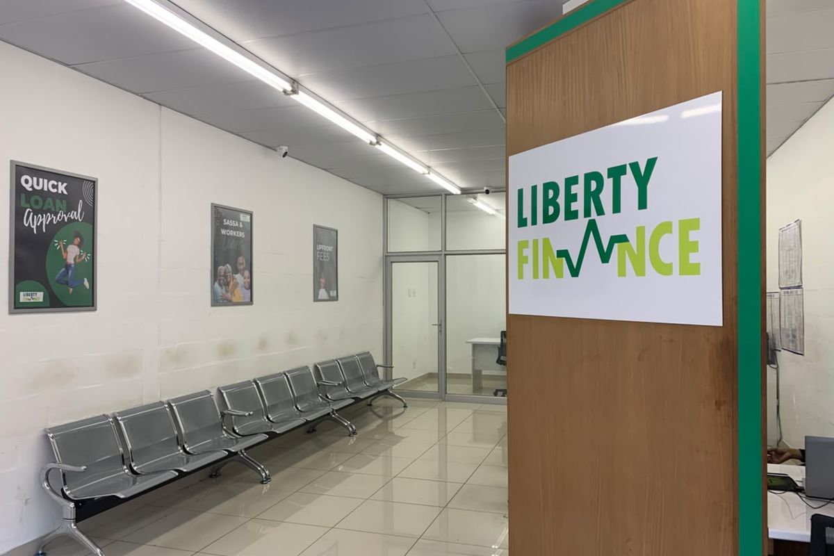 Commercial office entry area featuring tiled flooring, fluorescent lighting, and a glass partition, currently utilized as a waiting area for a finance office.