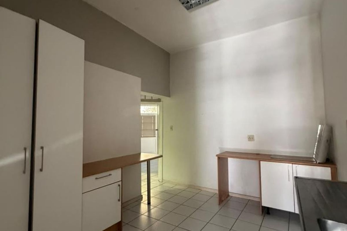 A functional kitchen space featuring tiled flooring, built-in cabinetry, and a stainless steel sink, currently vacant and ready for updates.