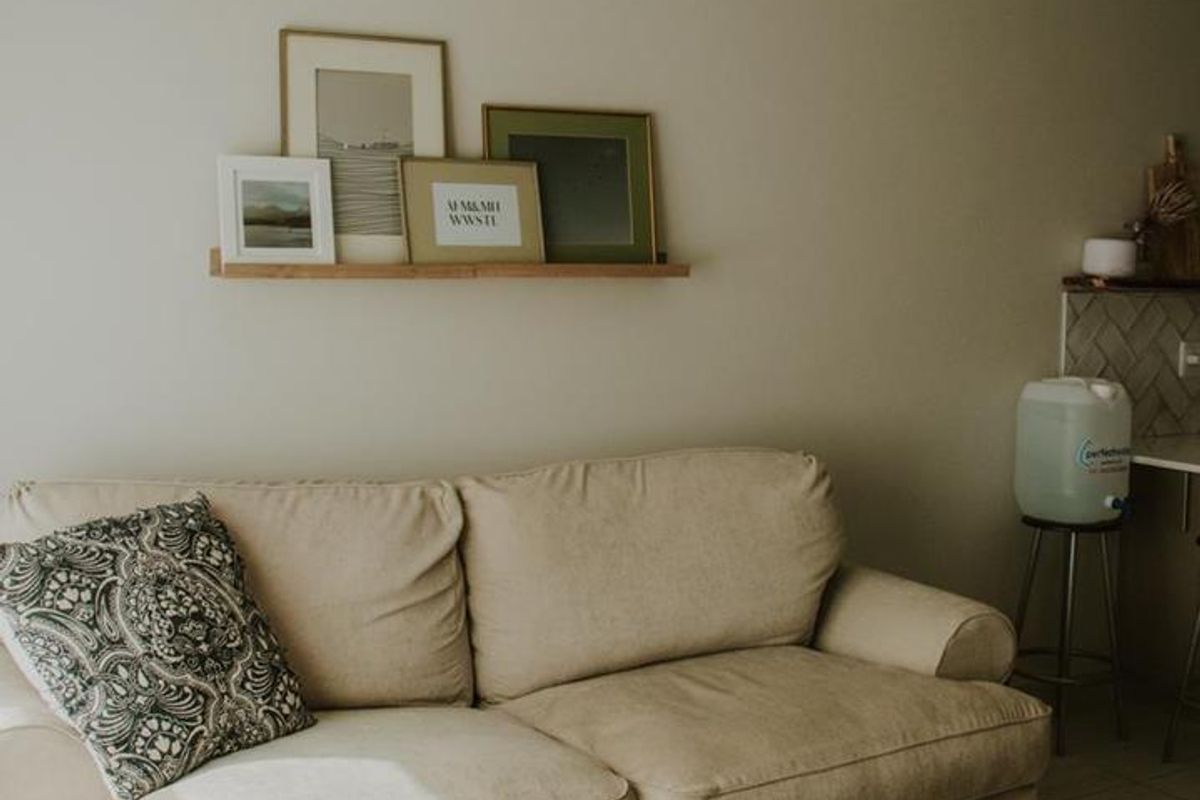 A cozy living room area featuring neutral wall tones, coving, and tiled flooring, creating a comfortable and inviting atmosphere.