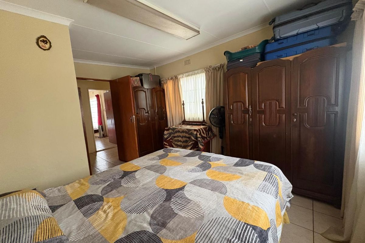 A functional bedroom featuring tiled flooring, built-in cupboards, and a standard ceiling light fixture.