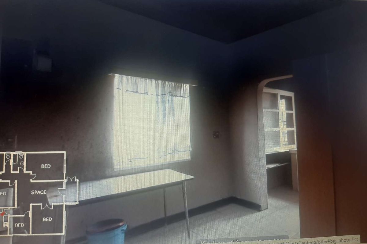 Interior view of a room showing significant fire or smoke damage to the walls and ceiling, with an arched doorway leading to an adjacent space.