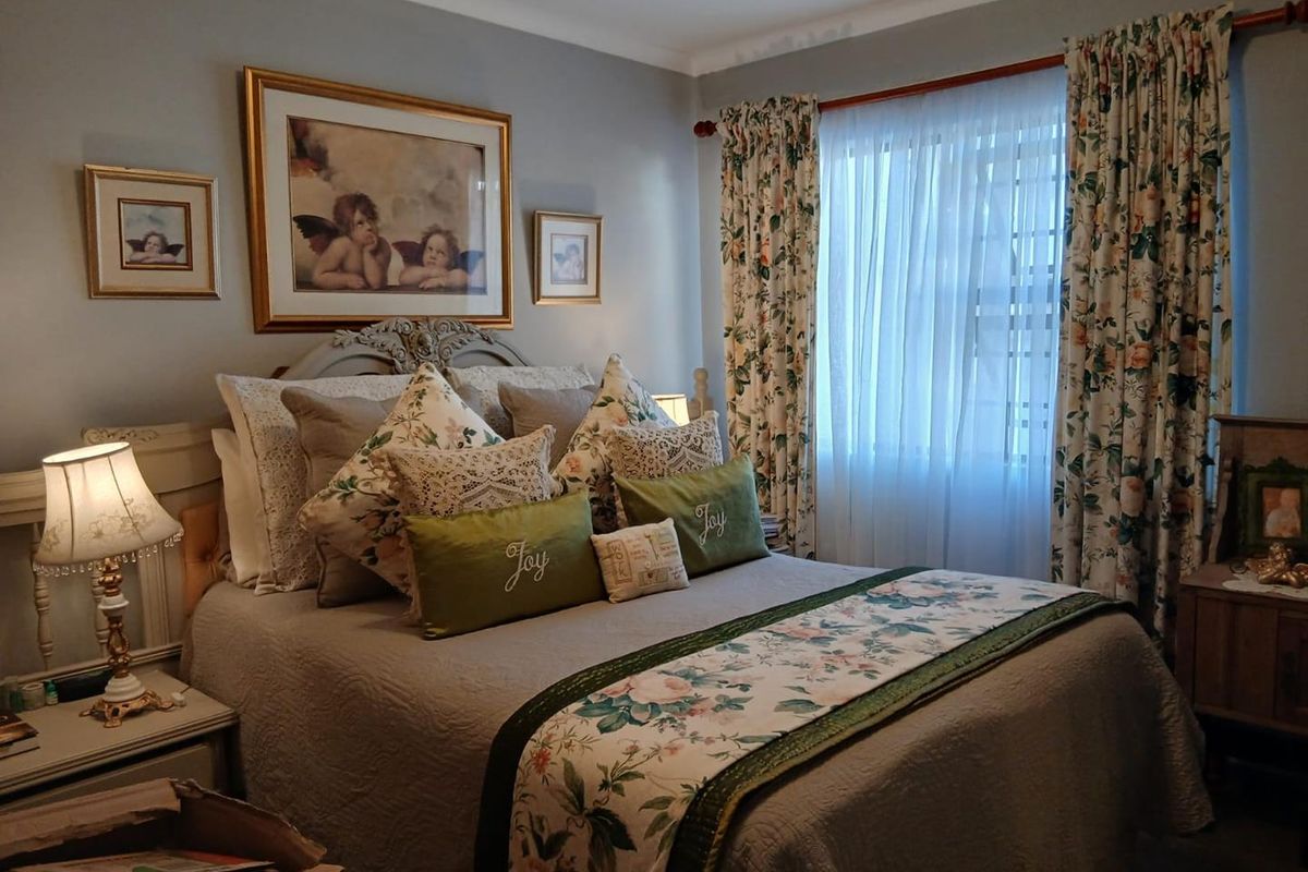 A cozy bedroom featuring neutral wall tones, a window with curtain treatments, and a classic layout suitable for a comfortable sleeping space.