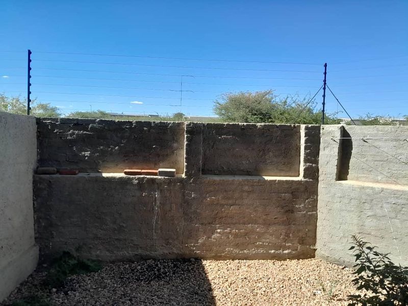 A private rear courtyard area featuring a masonry boundary wall with integrated electric fencing and gravel ground cover.