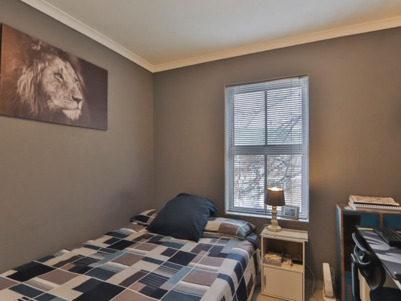 A bedroom featuring grey walls, cove cornicing, and a window fitted with venetian blinds.