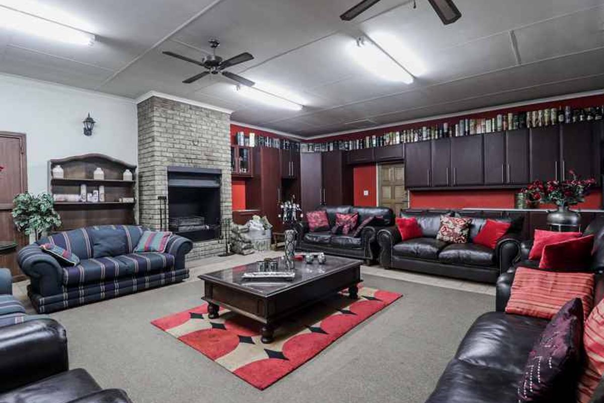 Spacious living room featuring a brick fireplace, extensive built-in cabinetry, and ceiling fans, offering a functional layout with ample storage.