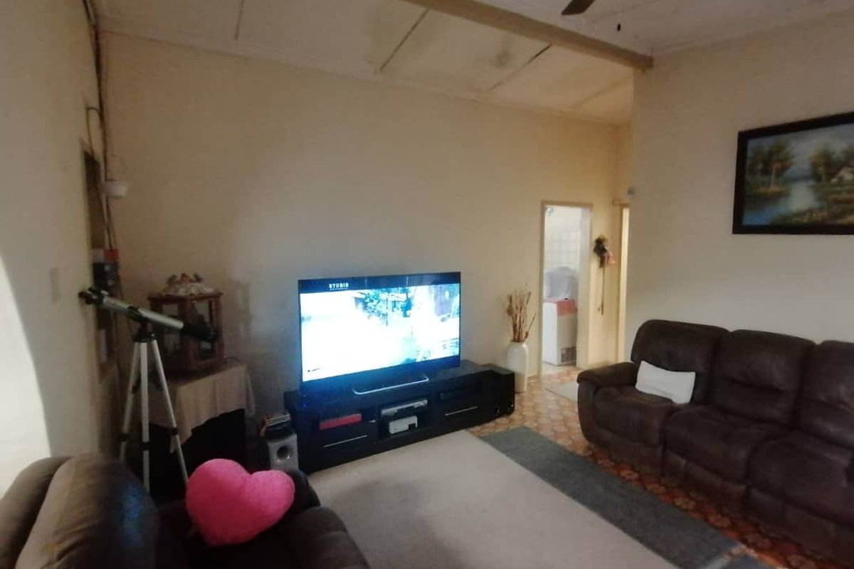 A living room area featuring tiled flooring and a ceiling fan, providing a functional space for relaxation.