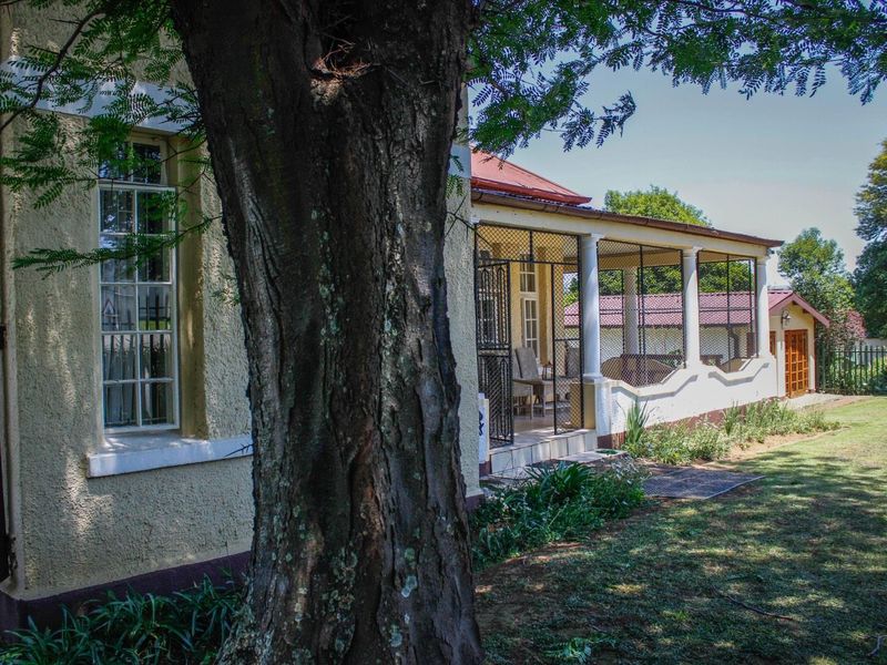 A view of the rear exterior of the guest house, featuring a covered patio area with security gates and a well-maintained garden.