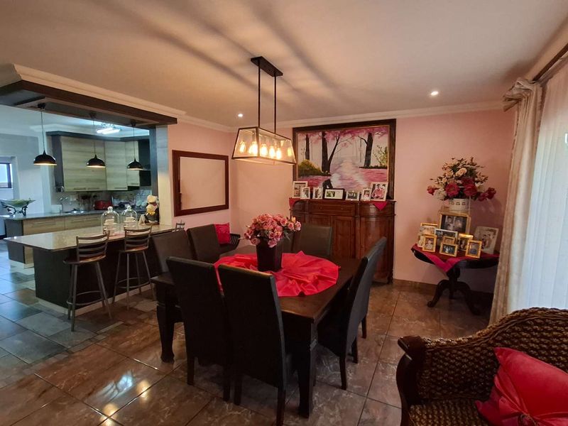 Open-plan living and dining area featuring a modern kitchen with a central island, tiled flooring, and contemporary pendant lighting.