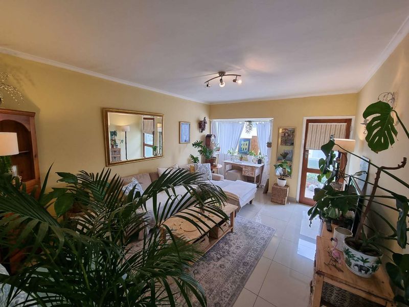 A bright living room featuring tiled flooring, a ceiling light fixture, and direct access to an outdoor area through a glass-paneled door.