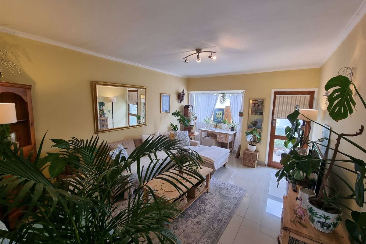 A bright living room featuring tiled flooring, a ceiling light fixture, and direct access to an outdoor area through a glass-paneled door.