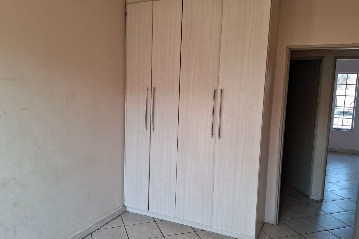 A clean, empty bedroom featuring light-toned built-in wardrobes and neutral tiled flooring, offering a blank canvas for personalization.