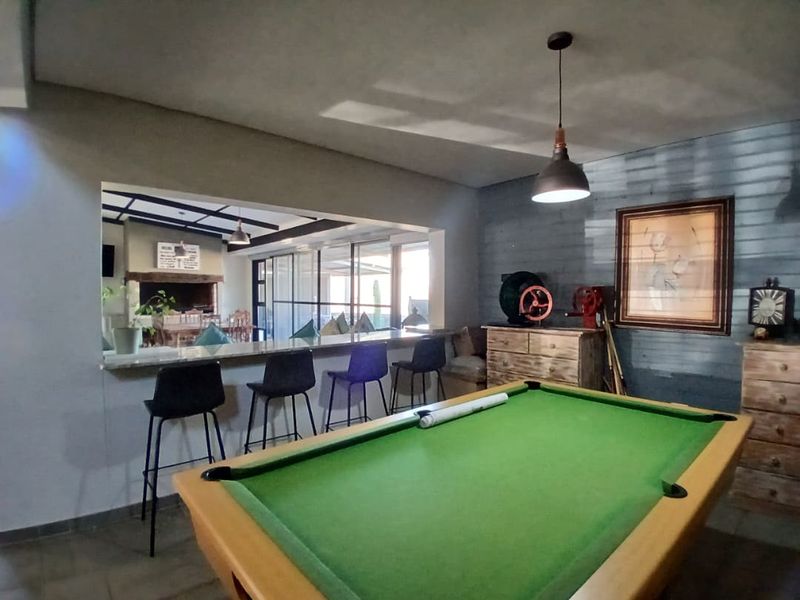 Spacious living area featuring a breakfast bar, exposed brick wall, and pendant lighting, with an open-plan connection to an adjacent dining space.