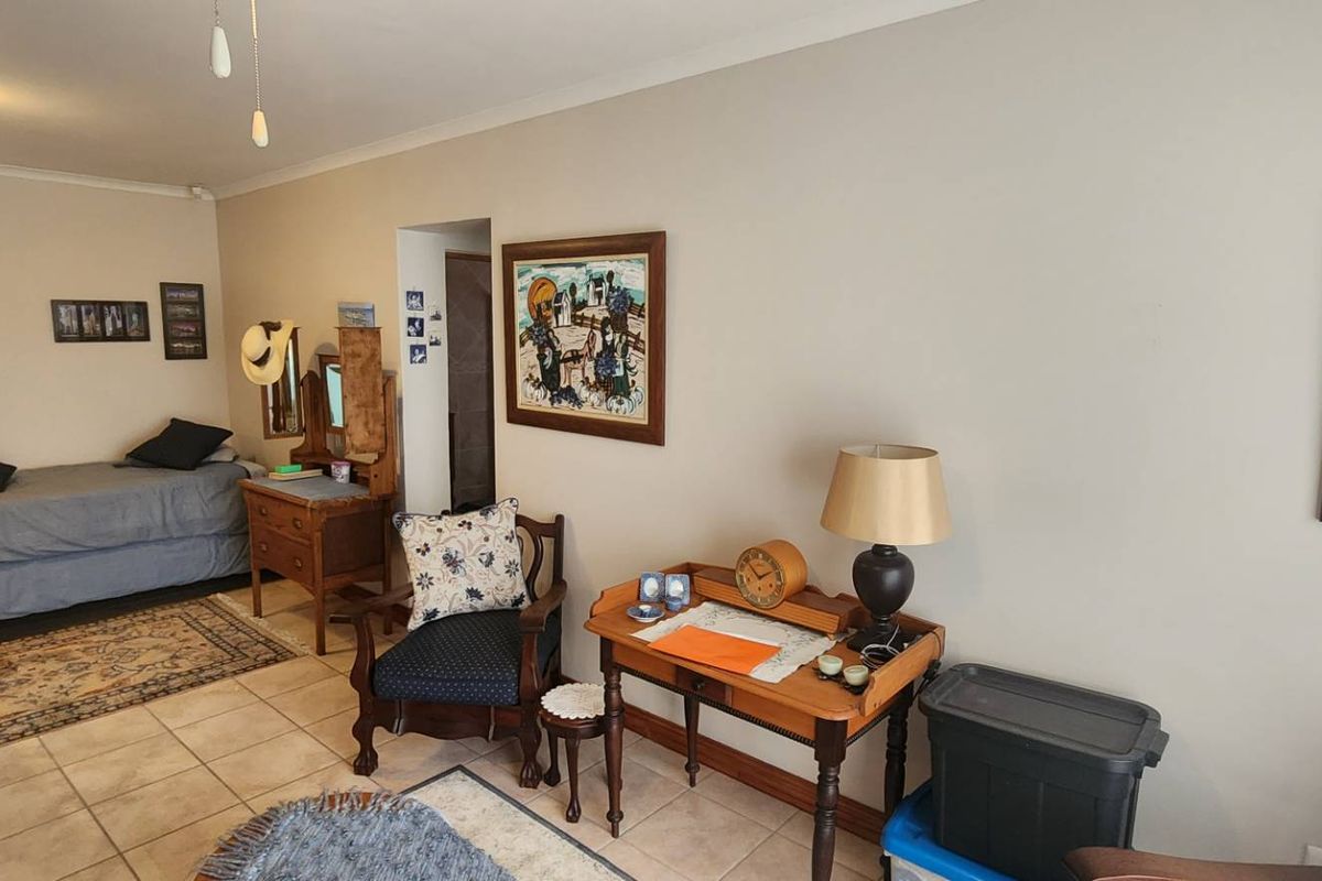A multi-purpose living area featuring tiled flooring and neutral wall finishes, currently utilized as a combined bedroom and sitting space.