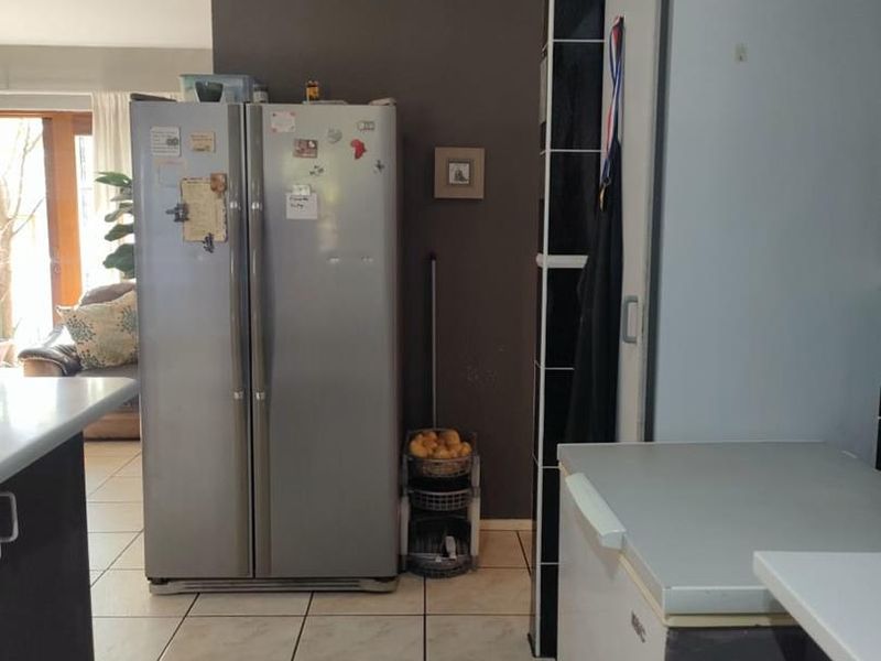 A kitchen area featuring tiled flooring and dark accent wall tiling, providing a functional layout with integrated appliance spaces.