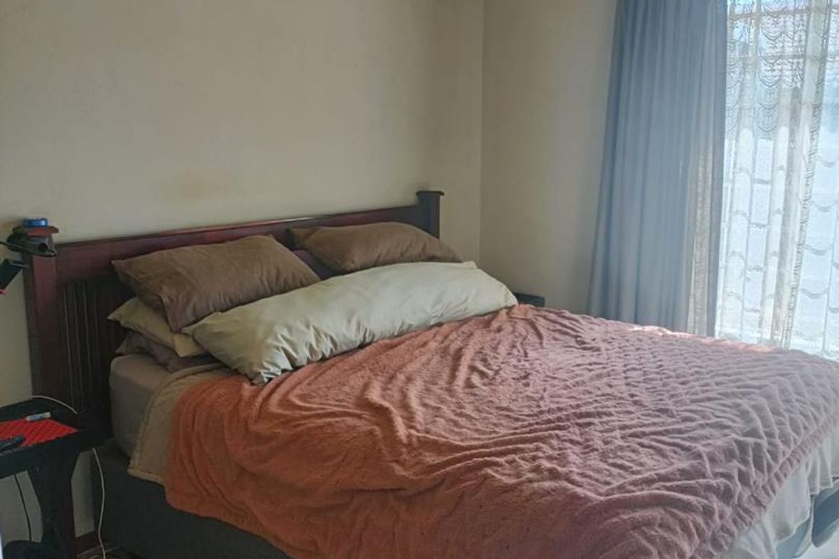 A bedroom featuring tiled flooring and a wall-mounted air conditioning unit, providing a functional and comfortable living space.