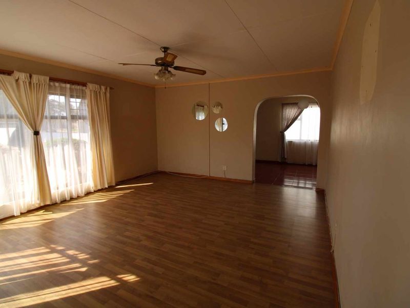 Spacious living room featuring laminate flooring, a ceiling fan, and an arched entryway leading to an adjacent room.
