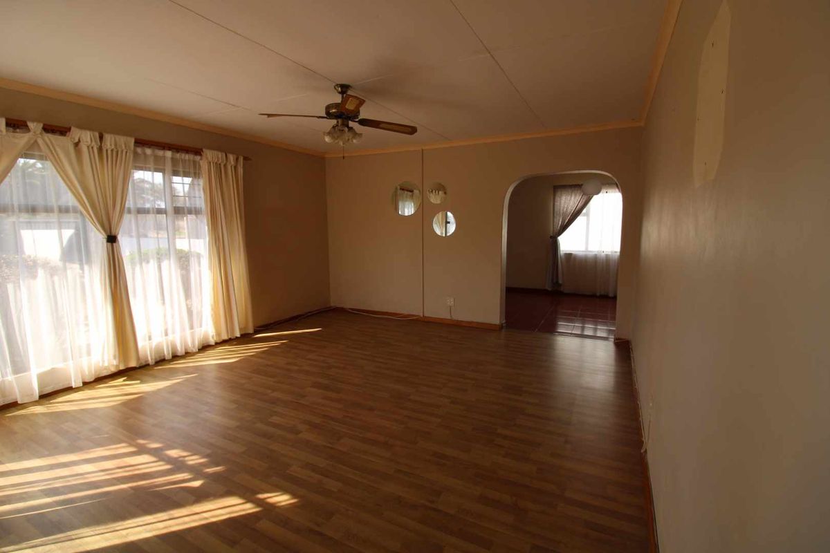 Spacious living room featuring laminate flooring, a ceiling fan, and an arched entryway leading to an adjacent room.