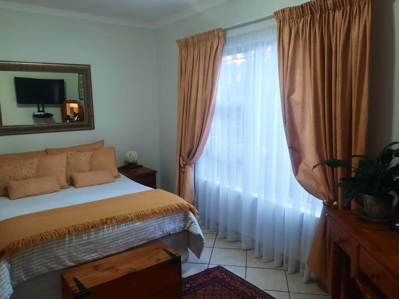 A bedroom featuring tiled flooring and window treatments, offering a functional space with neutral wall finishes.