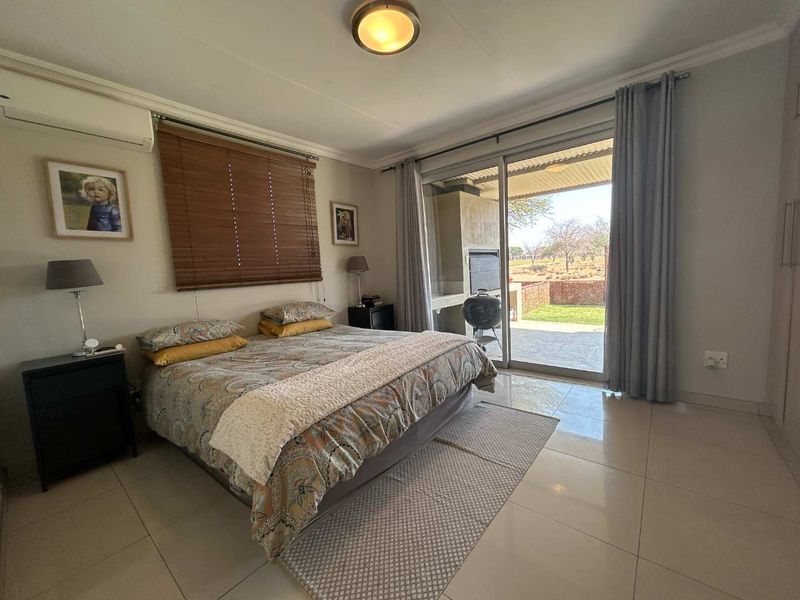 Spacious bedroom featuring tiled flooring, built-in cupboards, and a sliding glass door providing direct access to an outdoor patio area.