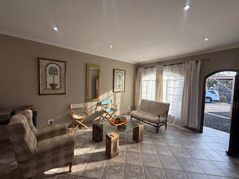 A bright living room featuring tiled flooring, recessed downlights, and arched windows that provide natural light and access to the exterior.