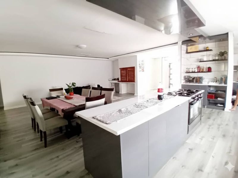Modern open-plan living and dining area featuring a sleek kitchen island with built-in hob, oven, and contemporary finishes throughout.